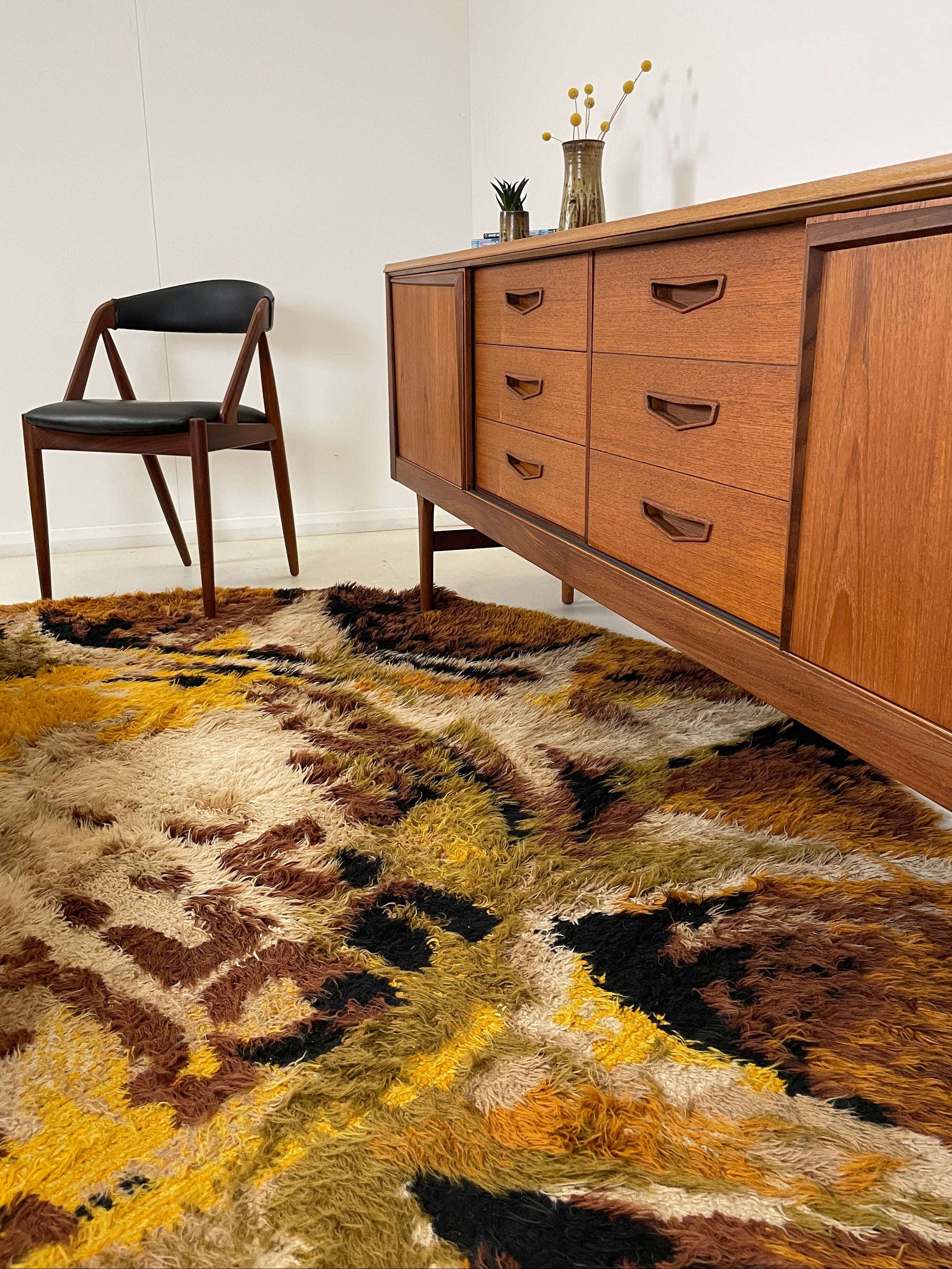 Wooden dresser with drawers and a patterned rug on a white floor.