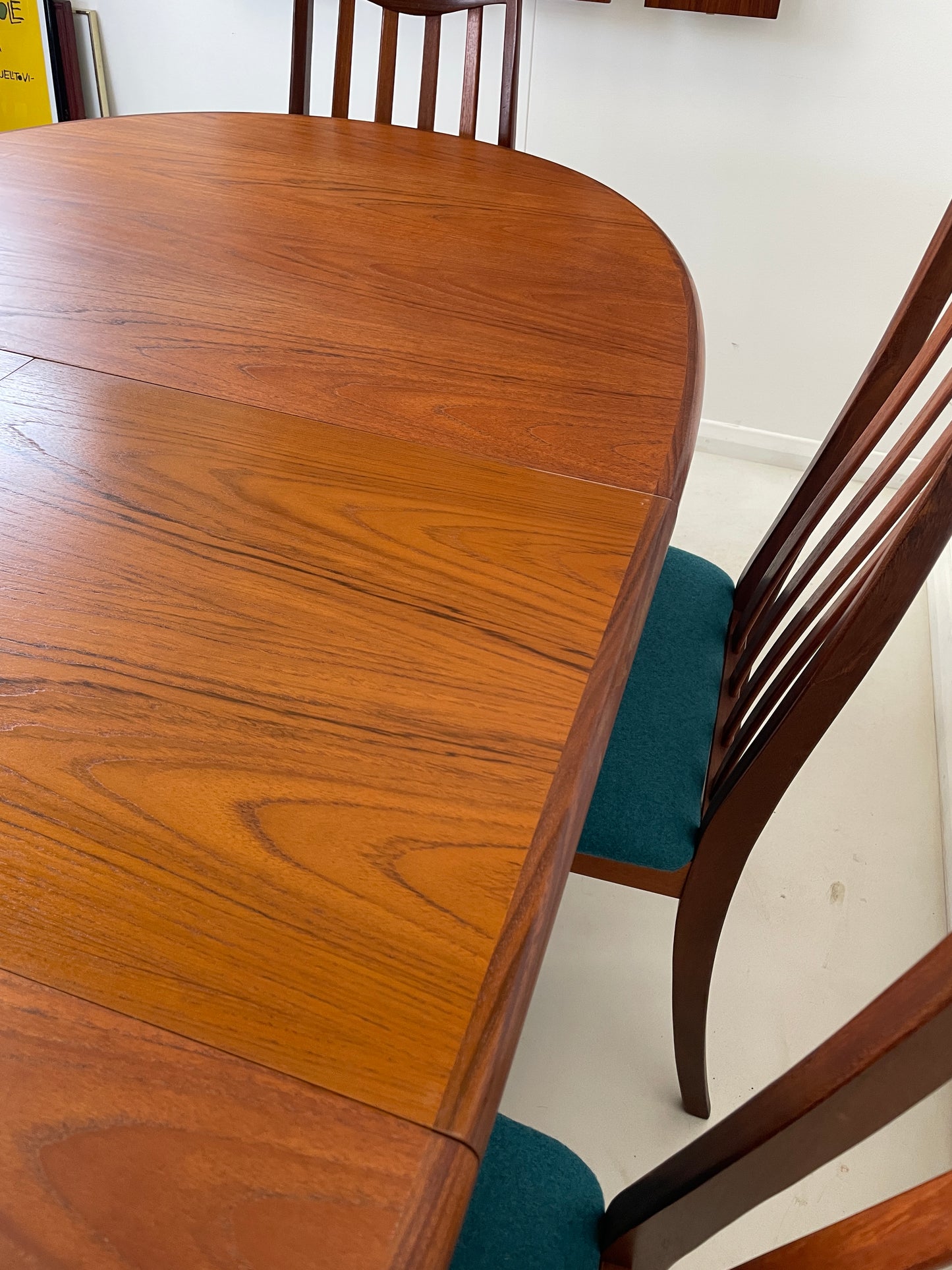 the extended table is in a white room with matching white floor. The extension middle section of the table has been photographed up close, you can see the colour of the wood is a teak glossy brown and it has been beautifully restore. 