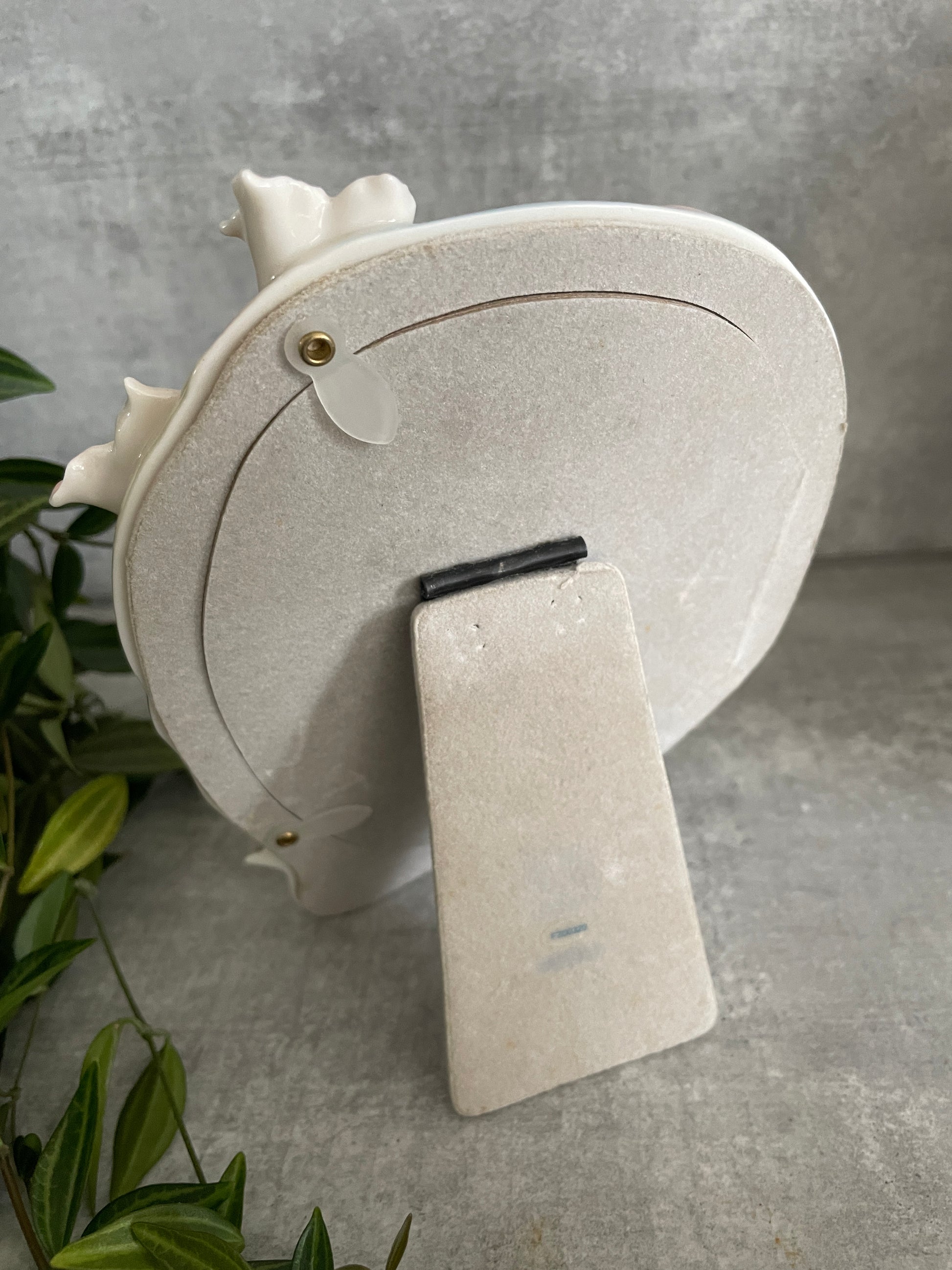 the back of the photo frame with a grey felted covering, a stand so the frame can be either standalone or wall mounted and two claps to fasten a photograph inside the frame with ease